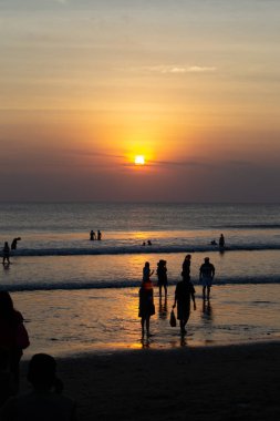 Gün batımında Bali Kuta plaj, İnsanlar oynuyor ve zevk