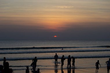 Gün batımında Bali Kuta plaj, İnsanlar oynuyor ve zevk