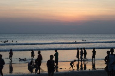 Gün batımında Bali Kuta plaj, İnsanlar oynuyor ve zevk
