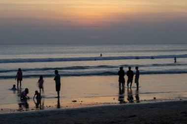 Gün batımında Bali Kuta plaj, İnsanlar oynuyor ve zevk