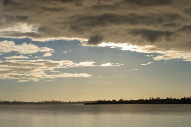 Bulutlar ve su ile gün batımında izole manzara