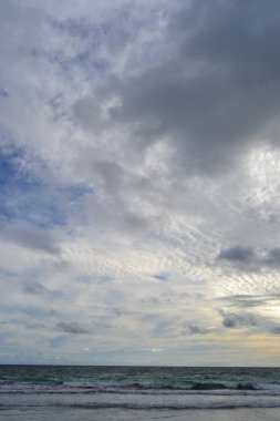 Ufukta bulutlar ve okyanus ile gün batımında bir plaj Manzara