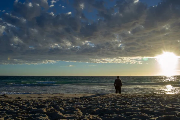 Contrasted landscape of a beach and a guy at sunset