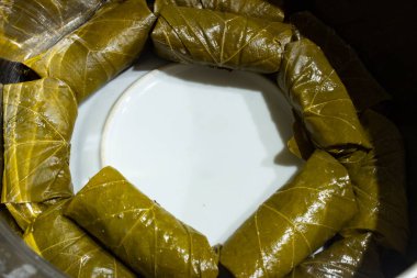 Üzüm yaprağına doldurulmuş. Pişirme sırasında üzüm yapraklarına doldurulmuş. Bir tencerede üzüm yaprağı doldurulmuş. Beyaz bir tabak tabaktabakta bir tencerede üzüm yaprakları dolması