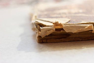 Beyaz yüzeyli eski bir kitap. Darmadağınık kitap. Beyaz bir yüzeyde yıpranmış bir kitap. Beyaz arka plan üzerine yıpranmış bir kitap