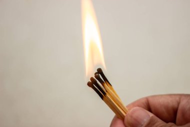 Elinde ışıklı maç. Beyaz arka planda aydınlatılmış bir eşleşme. Beyaz arka planda elde ışıklı eşleşme. Elinde yanan maç. Beyaz arka planda eşleşme yazma