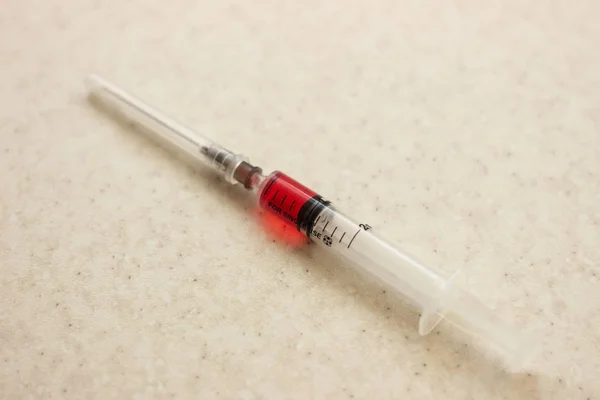 白い背景に赤い溶液と注射器。赤い溶液が付いている医学の注射器。白い表面に赤い溶液が付いている医学の注射器 — ストック写真