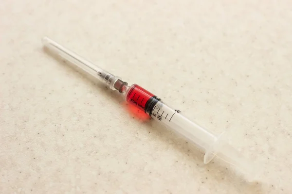 白い背景に赤い溶液と注射器。赤い溶液が付いている医学の注射器。白い表面に赤い溶液が付いている医学の注射器 — ストック写真