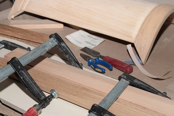 the detail of the wooden furniture facade is tightened into a clamp for repair on the desktop