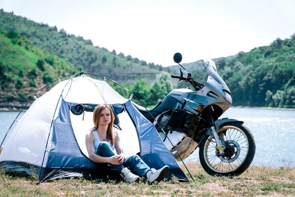 Gezgin. kız bir çadır, dağlar ve nehir arka planda, turizm motosiklet, road macera gezisi, gün ışığı, dinlenme