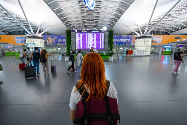 KYIV, UKRAINE - 23 Ağustos 2020: Sırt çantalı kız Kyiv 'deki Uluslararası Havalimanı Boryspil' e varış ve uçuş çizelgesine bakıyor. İyi akşamlar, gece..
