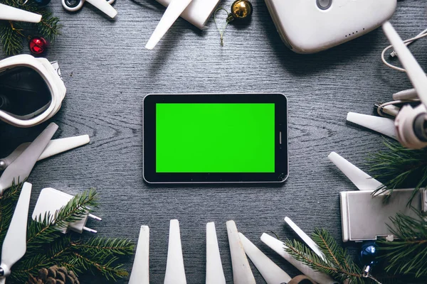 Tablet with green screen, Drone equipment, control panel on the background of a dark wooden table. Aerial shooting concept. best christmas tree new year present gift.