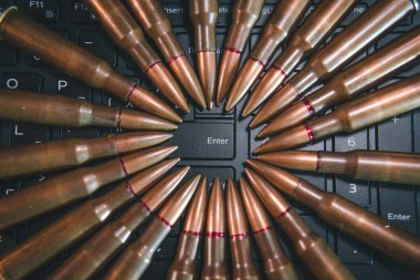 Bilgisayar klavyesinin kapatılması ve siber saldırıları temsil eden silah mermileri, gazetecilik, terörizm, teröristlere destek, Enter tuşuna basın.