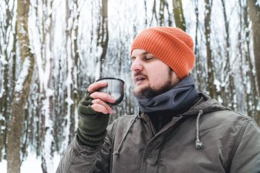 Turist sıcak çay içer, kar ormanında kahve içer. Açık havada macera tatili kavramı. Kış kampı. Örtü eşarp tüpü