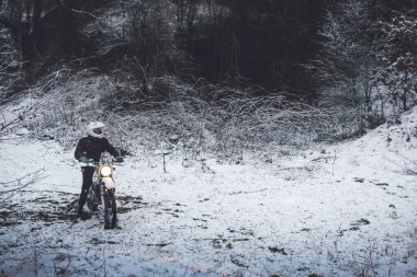 Kış motokrosunda motosikletli bir binici. Karlı bir ormanda kaydım. Enduro motosikletinin tekerleklerinin altındaki kar. off road dual spor seyahat turu, aktif yaşam tarzı konsepti