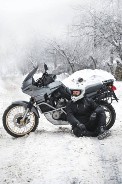Macera motosikletli bir binici. Kış eğlencesi Karlı bir gün. Motorsikletin tekerleklerinin altındaki kar. Enduro. off road dual spor seyahat turu, aktif yaşam tarzı konsepti. Kışlık giysiler, ekipmanlar, dikey fotoğraf