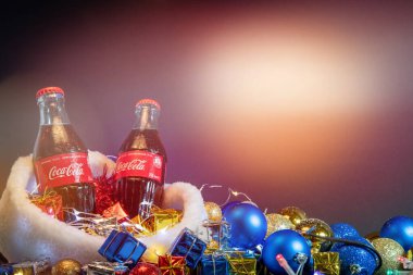 Khmelnytskyi, Ukrayna - 13 Aralık 2019: Coca-Cola Classic in a glass bottle on soft light shine with Christmas süslemeleri, hediyeler ve toplar, Santa hat 2020 konsepti, Ukrayna dili, kelimeler