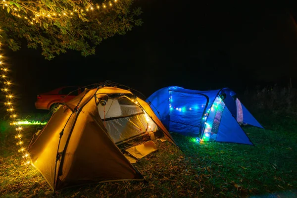 Tourist camping tents. Lights up. A night in a wilderness place. No bodies. Active lifestyle concept and equipment for recreation and hiking. Wide angle. Blue and brown