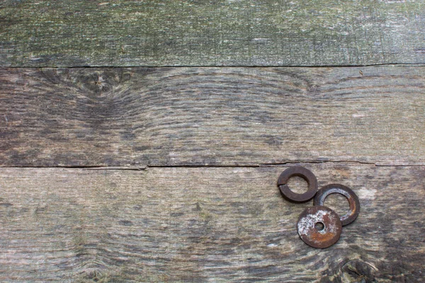 Weathered pallet wood boards as a background with rusty steel washers placed in the lower right corner.