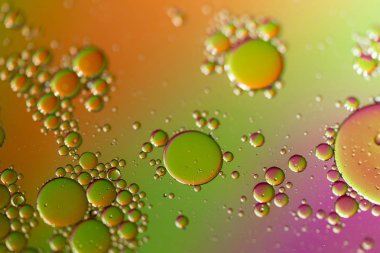 Bir portre renkli bir arka plan ile bir su yüzeyinde yağ damlacıkları.