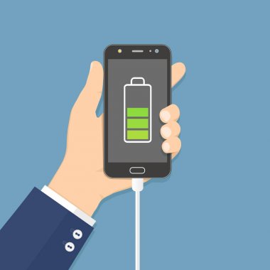 Şarj cihazı bağlı olan cep telefonunu tutan insan eli