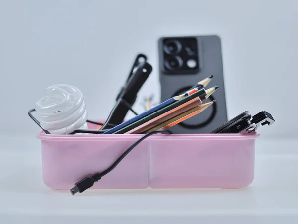 The image shows a pink plastic box with items arranged in different compartments.