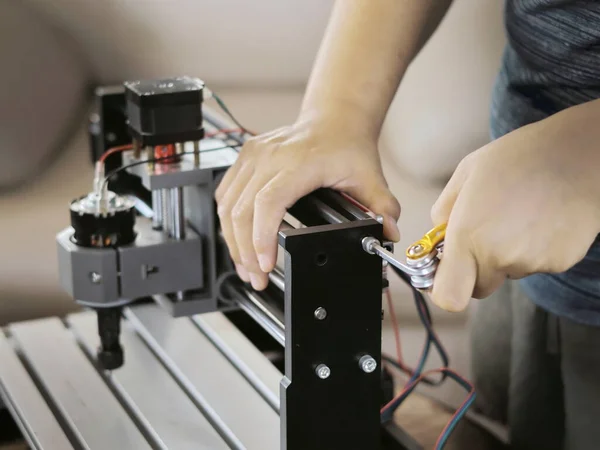 Close-up of a hand working on a piece of machinery, likely during assembly or maintenance.