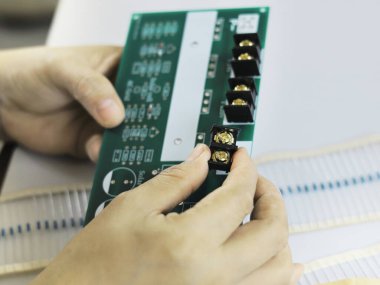 Image of electronic components held in hands for assembly onto a PCB board.