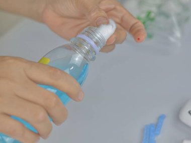 A close-up shot captures a hand holding a cotton ball at the mouth of a long, sterile bottle.