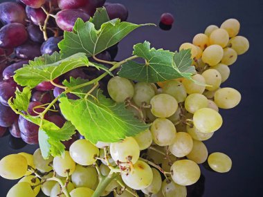 Tohumsuz sarı üzümler ve siyah parlak arka planda kırmızı üzümler.