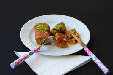 Siyah zemin uzerinde beyaz tabak icerisinde kadayif tatlisi