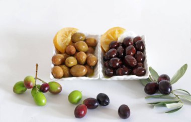 Beyaz arka planda siyah ve yeşil zeytinler.