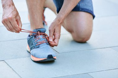 Parkta spor ayakkabılarına bağcıklar bağlayan adam