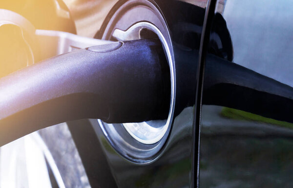 Кабель питания в электромобиле на электрозарядной станции. Роскошный черный электрический подзарядки
