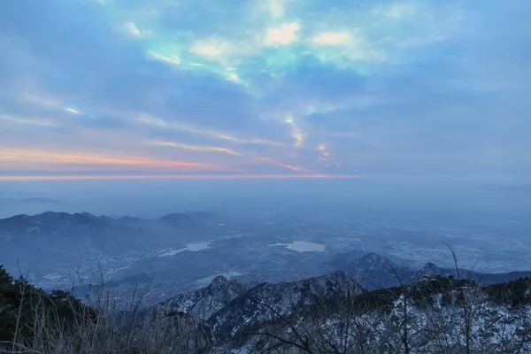 Tai Dağı dağın tepesinde. Tai 'an, Çin - kış 2017: Mount tai üstünden görünümü, Mount tai üst. Kayalıklar ve kar zirvelerde. Tepedeki çam ağaçları. Uzaktaki dağlar belirdi. Bulutlar onu çelenmis. Gökyüzündeki bulutlar kalındı.