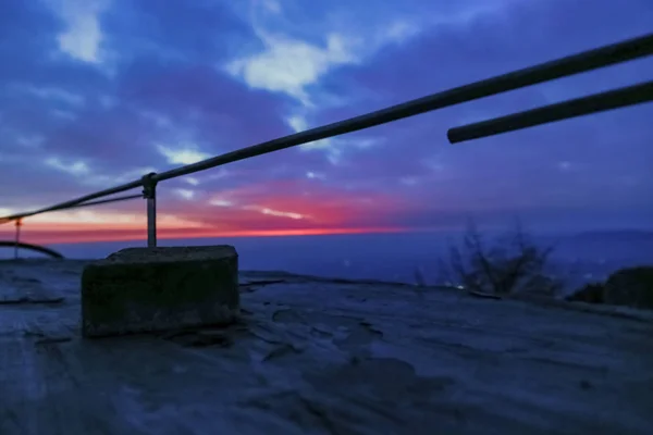 Iron railings and masonry on the observation deck. Waiting for sunrise atop mount tai.The observation deck has iron railings, and a piece of masonry.Overlooking is the sunrise scene about to begin