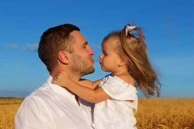 Mutlu aile - baba holding kız mavi yaz gökyüzü karşı bir buğday alan ortasında onun kollarında