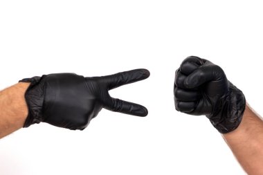 Siyah lateks eldiven elinde iki farklı hareketleri göster. Beyaz arka plan üzerinde izole. Kavram oyun taş makas kağıt