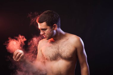 Stüdyo elinde beyzbol renkli duman siyah bir zemin üzerine poz bir beyzbol oyuncusu ile kaslı sporcu portresi. Profesyonel sporcu