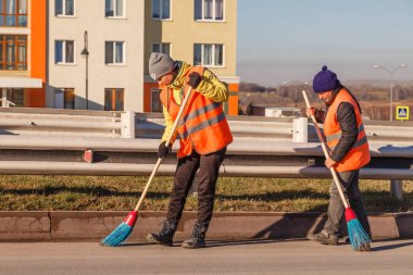 Kapıcı üniformalı kürek ve süpürgeler ile yaprakları ve enkaz yol boyunca süpürme. Temiz şehir, açık iş ve şehir kış gelmeden temizlik kavramını