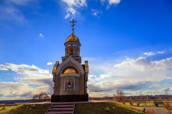 Old Christian chapel in Kemerovo with golden and gilded domes, brown granite walls against a sky, beautiful autumn landscape. Concept of faith in god, orthodoxy, prayer