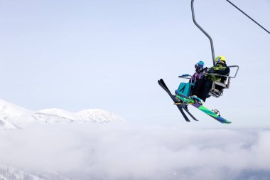 Rusya, Sheregesh 2018.11.17 snowboard ve profesyonel kıyafet tırmanış teleferik yukarı kayakçı dağların arka planda gökyüzü ve dağ doruklarına kaldırın. Kayak Emanet, açık dinlenme, dostluk kavramı