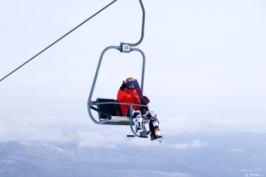 Rusya, dağlar gökyüzü ve dağ zirveleri arka plan üzerinde profesyonel kıyafet tırmanış teleferik yukarı Sheregesh 2018.11.17 snowboard kaldırın. Kayak Emanet, açık dinlenme, dostluk kavramı