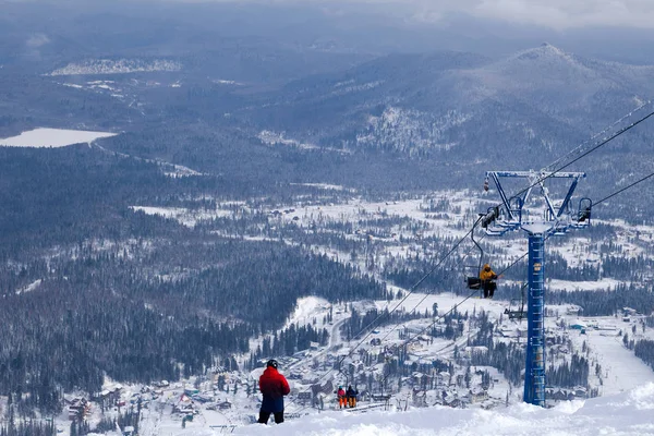 Ski lift, cable car funicular with open cabin on the background of valley, skiers, snowboarders, snow-capped mountains, evergreen trees. Concept of Alps resort, Georgia, Sochi, Matterhorn