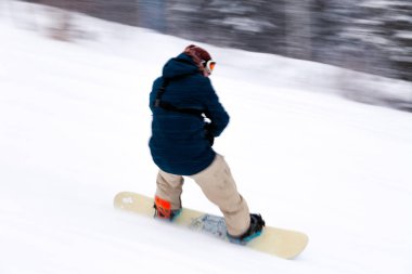 Rusya, Sheregesh 2018.11.18 profesyonel snowboard parlak spor giyim ve yokuş aşağı karlı güneşli yüksek dağlarda kayak kıyafeti. Bulanıklık, yumuşak odak, nesne hareket. Kavram freeride
