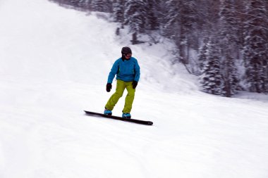 Rusya, Sheregesh 2018.11.18 profesyonel snowboard parlak spor giyim ve yokuş aşağı karlı güneşli yüksek dağlarda kayak kıyafeti. Bulanıklık, yumuşak odak, nesne hareket. Kavram freeride
