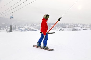 Rusya, Sheregesh 2018.11.18 Snowboarder profesyonel kıyafeti bir dağlarda teleferik yukarı çık. Emanet Kayak, açık kalan kavramı