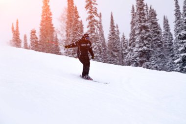 Rusya, Sheregesh 2018.11.18 profesyonel kayakçı parlak spor giyim ve yokuş aşağı karlı güneşli yüksek dağlarda kayak kıyafeti. Bulanıklık, yumuşak odak, nesne hareket. Güvenli dinlenme kavramı