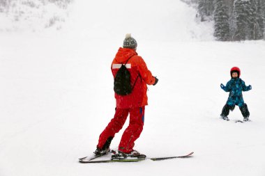 Rusya, Sheregesh 2018.11.18 antrenör parlak spor genç küçük çocuk ve kask dağ tatil kayak yapmak öğretmek. Bulanıklık, yumuşak odak, nesne hareket. Çocuk spor, Emanet kavramı