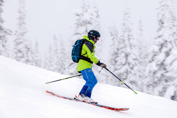 Russia, Sheregesh 2018.11.18 Professional skier in bright sportswear and outfit skiing downhill in snowy sunny high mountains. Blur, soft focus, object in motion. Concept of safe rest